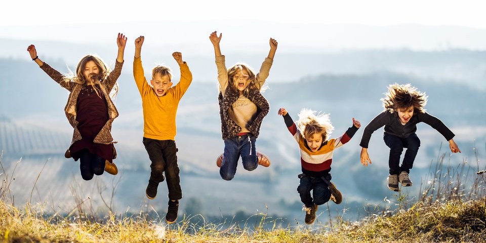 Kinder springen auf einer Wiese